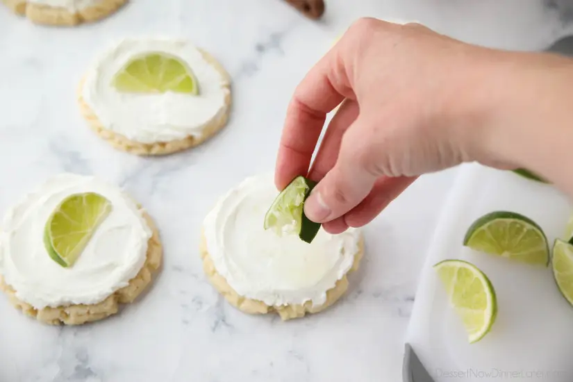 Coconut Lime Sugar Cookies - an easy sugar cookie recipe with a tropical fruit twist. You'll love these moist sugar cookies with a hint of lime, creamy coconut frosting, and a fresh lime wedge to squeeze on top. A Twisted Sugar copycat recipe.