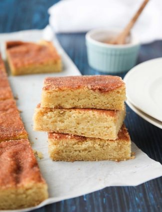 Snickerdoodle Bars transform classic snickerdoodle cookies into easy-to-make blondies. Thick, soft, buttery cookie bars are topped with plenty of cinnamon-sugar. These flavorful, melt-in-your-mouth dessert bars make enough to serve a crowd. Perfect for potlucks, picnics, and parties.