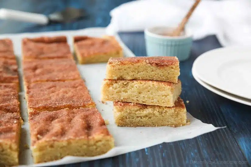 Snickerdoodle Bars transform classic snickerdoodle cookies into easy-to-make blondies. Thick, soft, buttery cookie bars are topped with plenty of cinnamon-sugar. These flavorful, melt-in-your-mouth dessert bars make enough to serve a crowd. Perfect for potlucks, picnics, and parties.