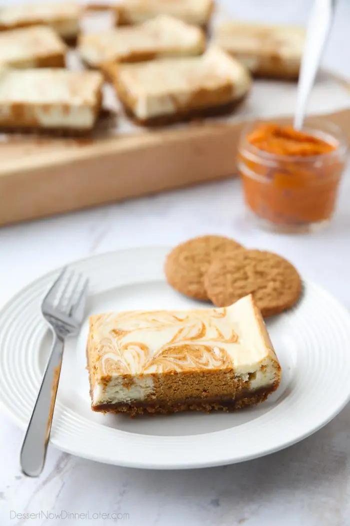 Pumpkin Swirl Cheesecake Bars have a buttery gingersnap crust, with ribbons of creamy vanilla and spiced pumpkin cheesecake marbled on top. A delicious dessert for fall or Thanksgiving.
