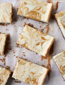 Pumpkin Swirl Cheesecake Bars have a buttery gingersnap crust, with ribbons of creamy vanilla and spiced pumpkin cheesecake marbled on top. A delicious dessert for fall or Thanksgiving.