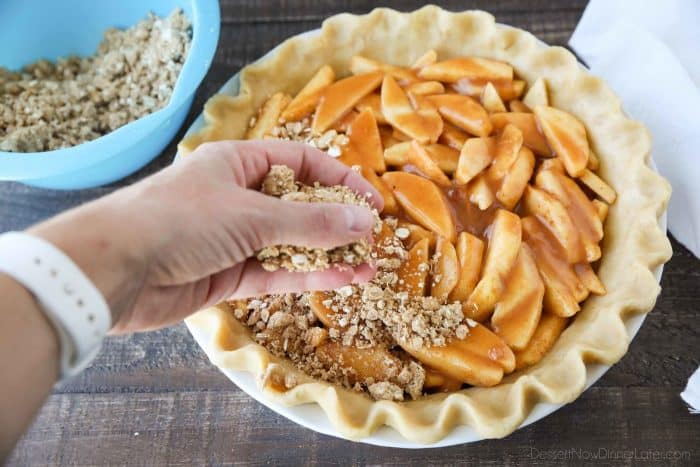 An oat and crumb streusel is sprinkled over glazed apples in an unbaked pie crust.