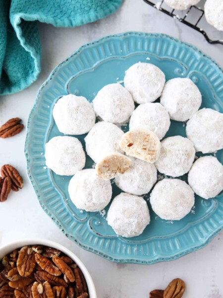 Snowball Cookies are round buttery shortbread cookies with chunks of pecans all rolled in powdered sugar. They melt in your mouth and are a delicious Christmas cookie.