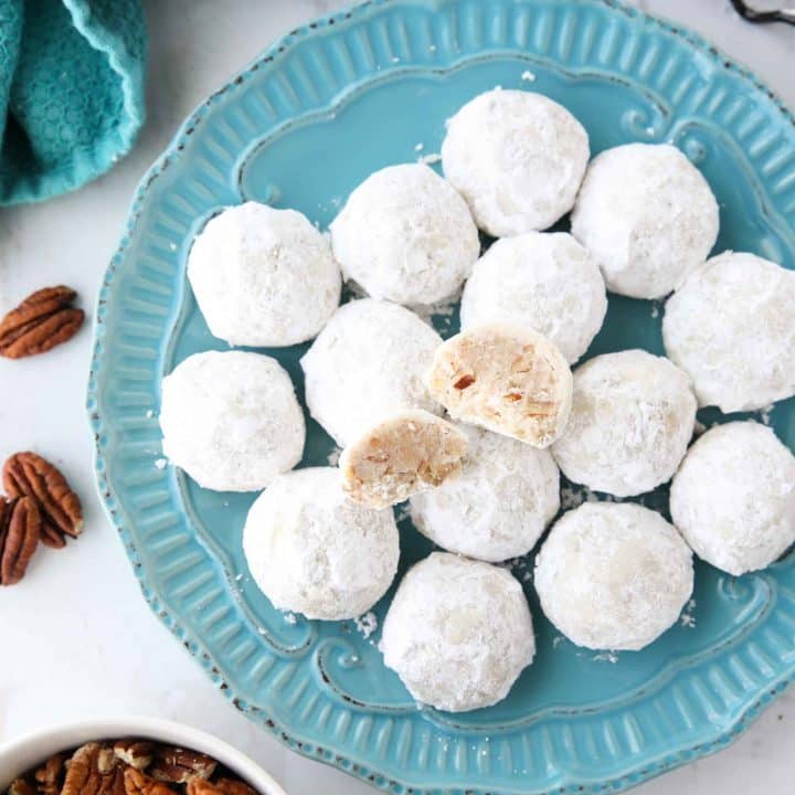 Snowball Cookies are round buttery shortbread cookies with chunks of pecans all rolled in powdered sugar. They melt in your mouth and are a delicious Christmas cookie.