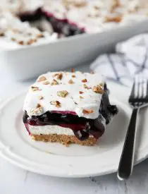 Blueberry Delight (aka Blueberry Lush) is an easy layered dessert with a graham cracker and pecan crust, no bake cheesecake, blueberry pie filling, and cool whip topping. A light, fruity, and delicious summer dessert with minimal baking.
