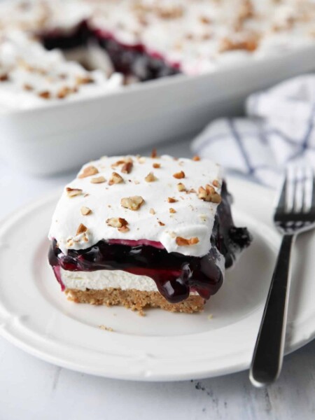 Blueberry Delight (aka Blueberry Lush) is an easy layered dessert with a graham cracker and pecan crust, no bake cheesecake, blueberry pie filling, and cool whip topping. A light, fruity, and delicious summer dessert with minimal baking.