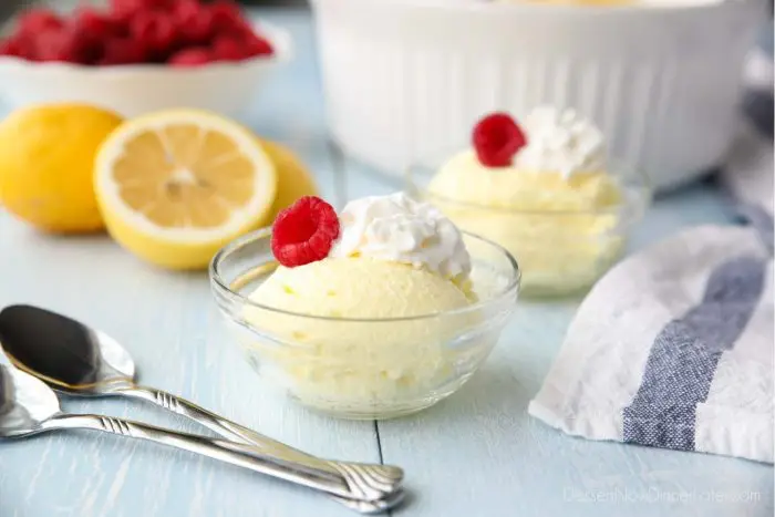 Individual bowls of lemon fluff dessert topped with whipped cream and fresh raspberries.
