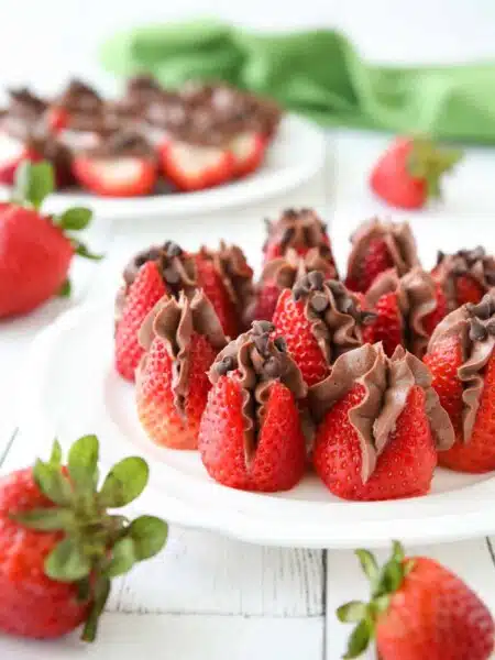 Plate of strawberries filled with no bake chocolate cheesecake filling and topped with mini chocolate chips.