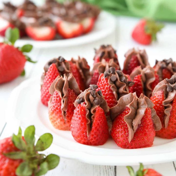 Plate of strawberries filled with no bake chocolate cheesecake filling and topped with mini chocolate chips.