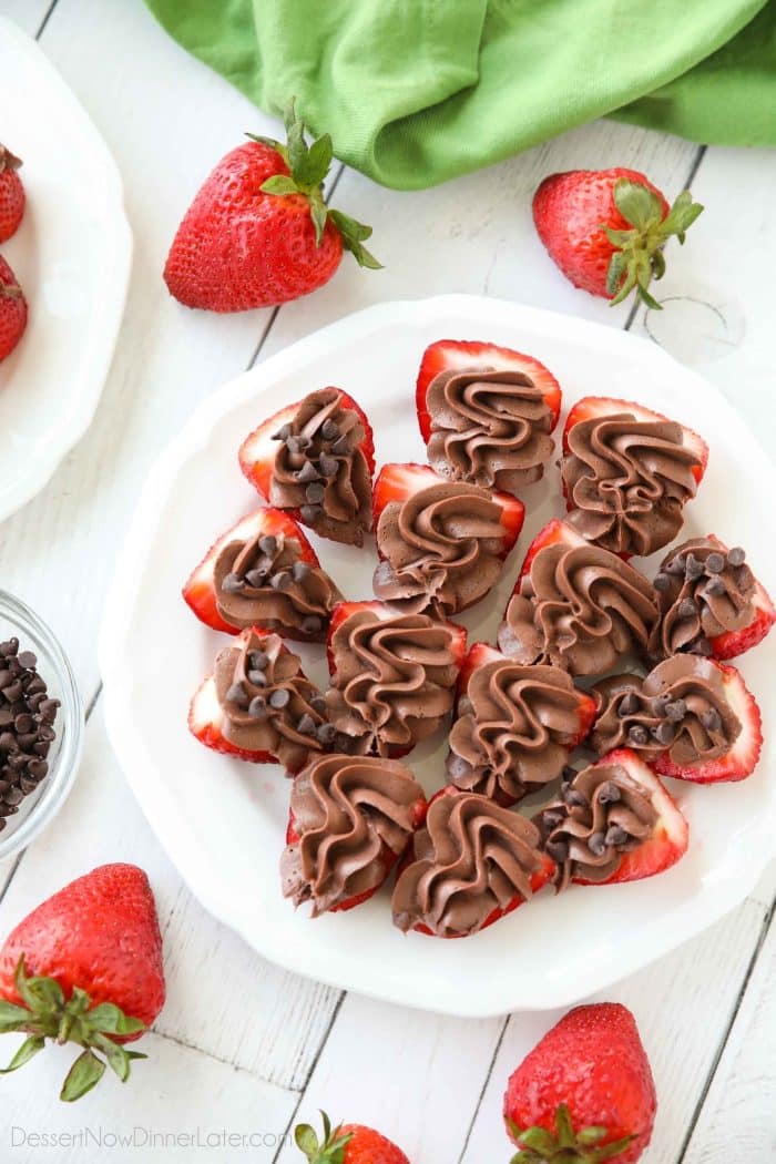 Plate of strawberries cut in half and topped with no bake chocolate cheesecake filling.