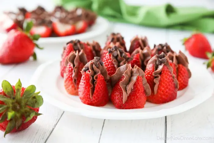 Plate of strawberries filled with no bake chocolate cheesecake filling and topped with mini chocolate chips.