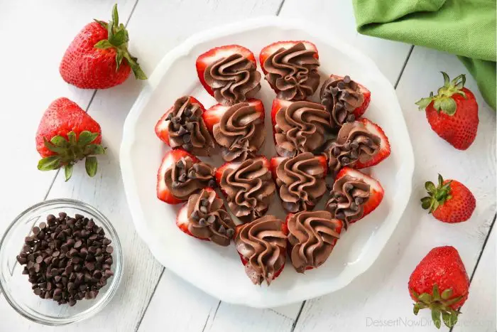 Plate of strawberries cut in half and topped with no bake chocolate cheesecake filling.