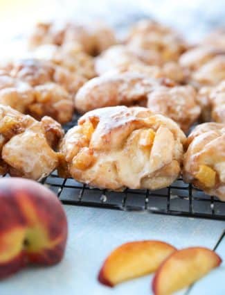 Glazed Peach Fritters Donuts on a cooling rack.