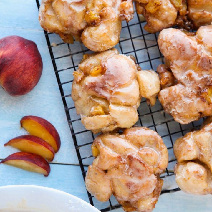 Glazed Peach Fritters Donuts on a cooling rack.