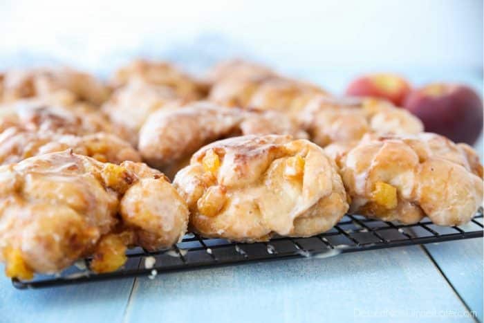 Glazed Peach Fritters Donuts on a cooling rack.