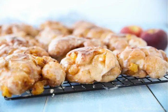 Glazed Peach Fritters Donuts on a cooling rack.