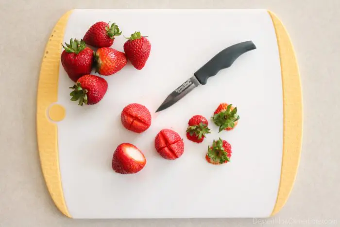 Strawberries with the leaves cut off and an "X" cut on the bottom.