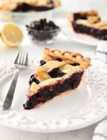 Slice of homemade blueberry pie made with frozen blueberries and simple ingredients to create a thick (not runny) pie filling from scratch.