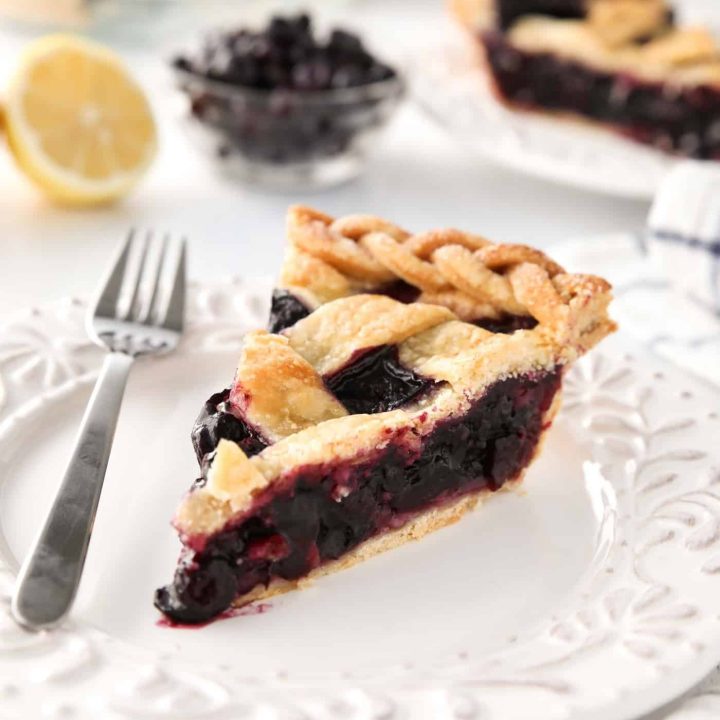 Slice of homemade blueberry pie made with frozen blueberries and simple ingredients to create a thick (not runny) pie filling from scratch.