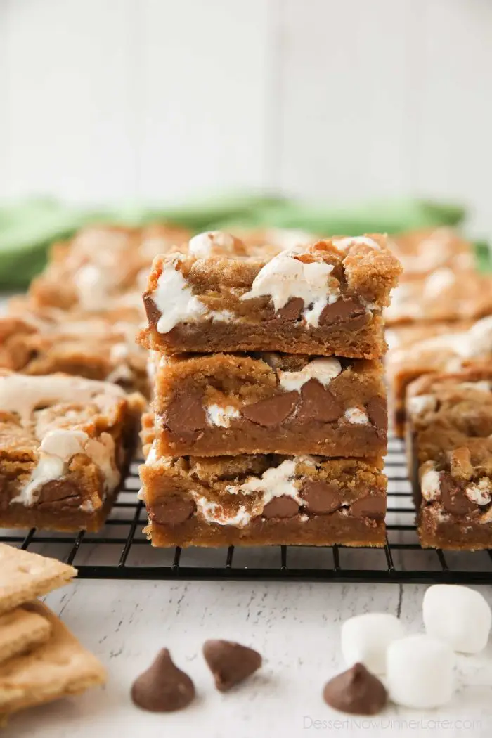 Three Smore's Bars stacked on top of each other with marshmallow fluff and chocolate chips oozing out. | Dessert Now Dinner Later