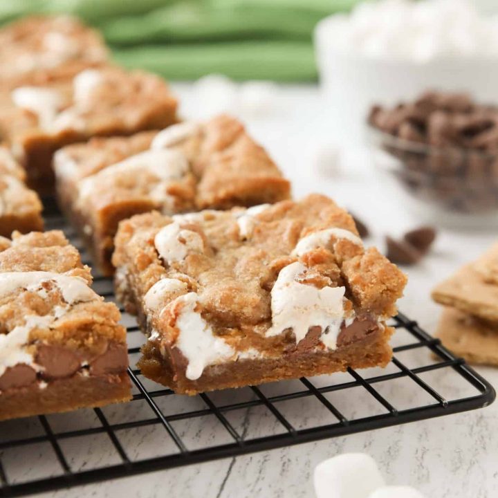 Gooey s'mores bars on a cooling rack with marshmallow fluff and chocolate chips in the center. | Dessert Now Dinner Later