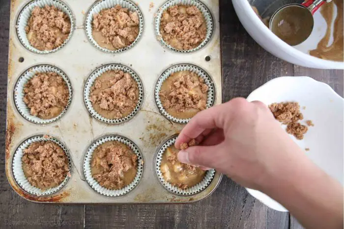 Sprinkling the crumb topping on the apple cinnamon batter filled muffin cups.