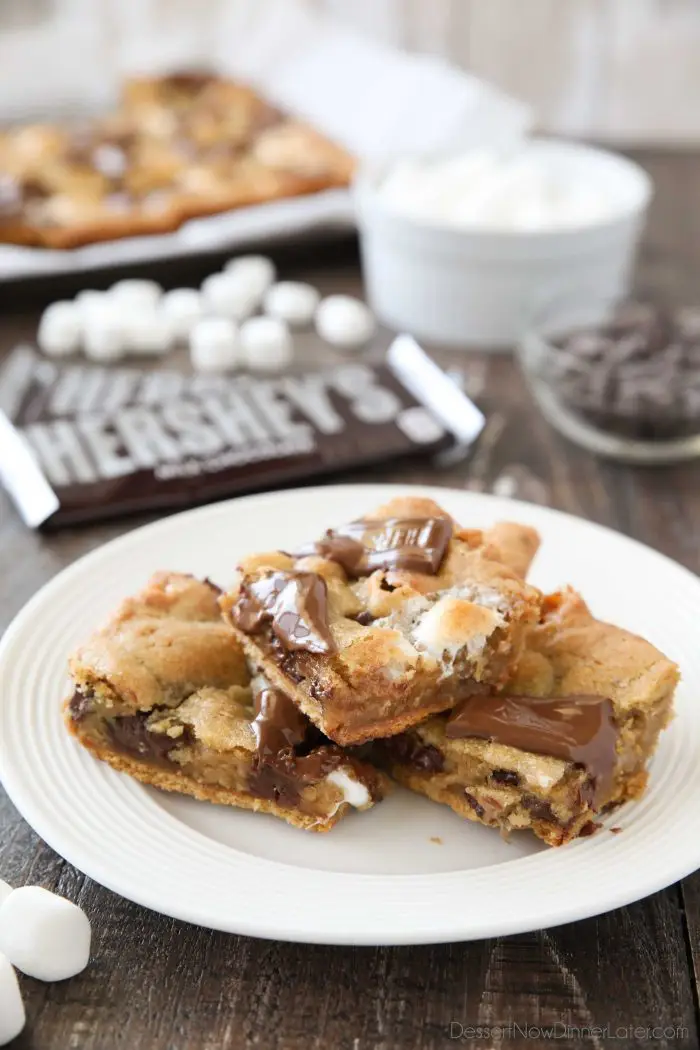 S'mores Cookie Bars are layered with graham crackers, cookie dough with marshmallows, and topped with chocolate bar pieces. It's an ooey gooey melty chocolate s'mores treat!