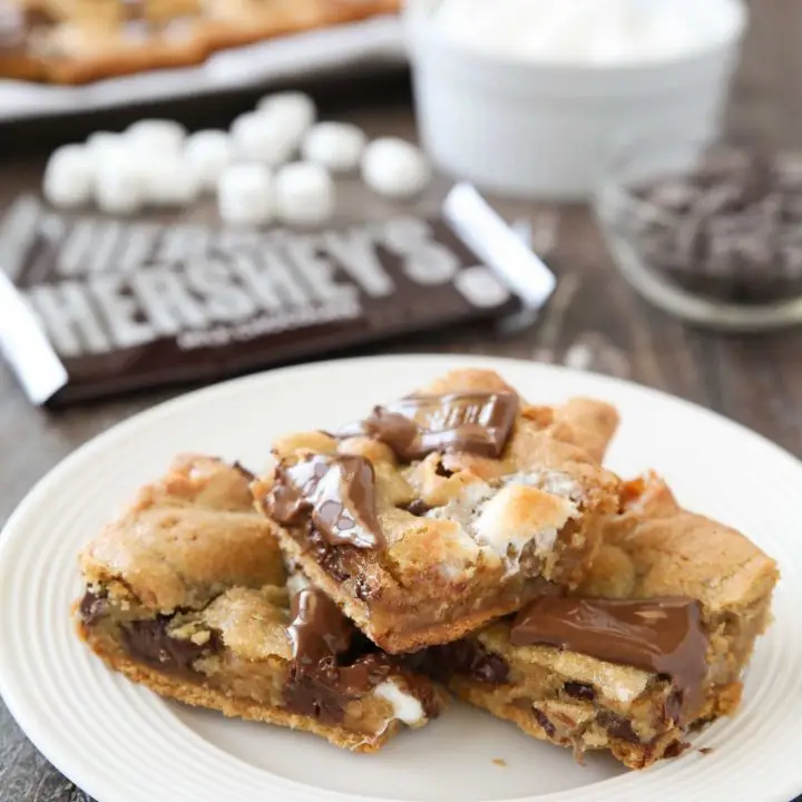 S'mores Cookie Bars are layered with graham crackers, cookie dough with marshmallows, and topped with chocolate bar pieces. It's an ooey gooey melty chocolate s'mores treat!