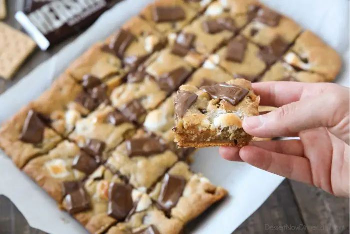 Warm and gooey s'mores cookie bars with graham crackers on bottom, marshmallows inside, and chocolate pieces on top.
