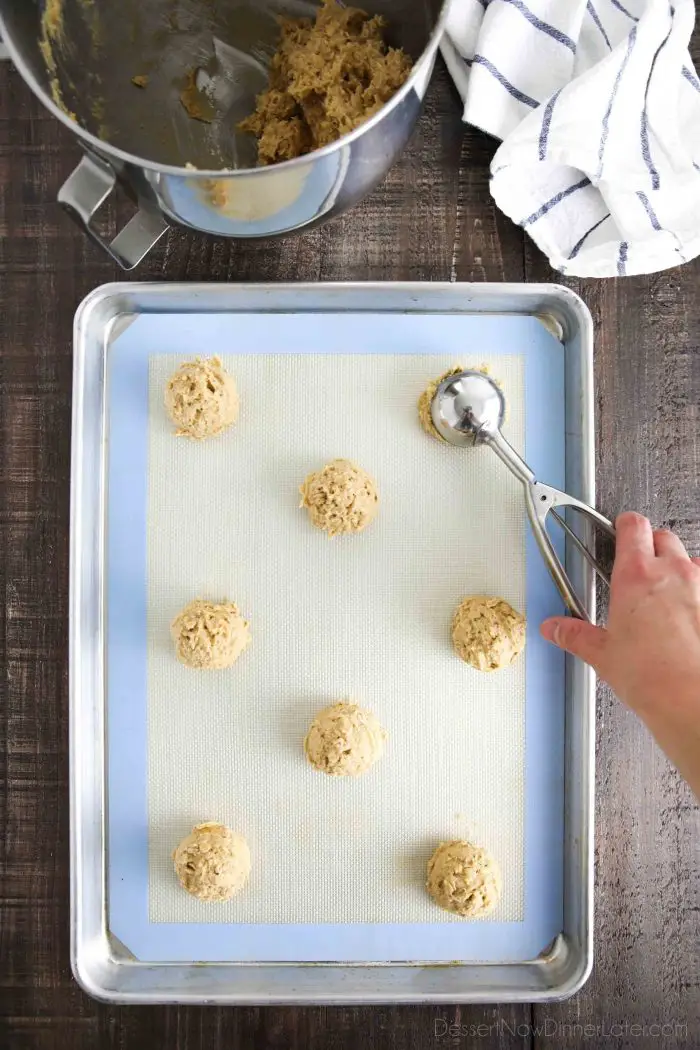 Scooping peanut butter oatmeal cookie dough onto a cookie sheet.