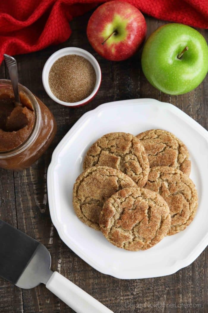 Crinkle topped apple butter cookies on plate with apple butter, cinnamon sugar, and fresh apples nearby.