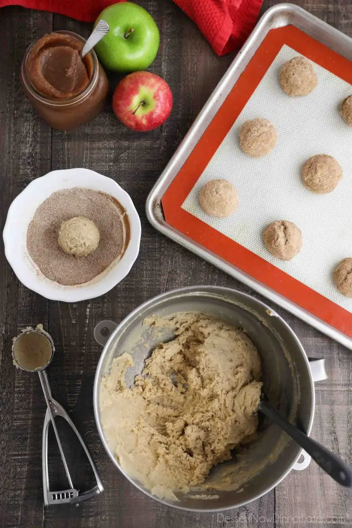 Cookie dough shaped into balls that have been coated in a bowl of cinnamon sugar.