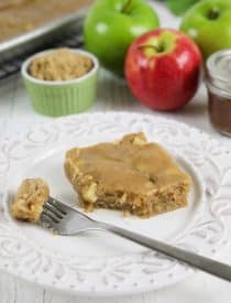 Apple sheet cake made with fresh apples and a brown sugar glaze on top. A fork full on plate ready to eat.