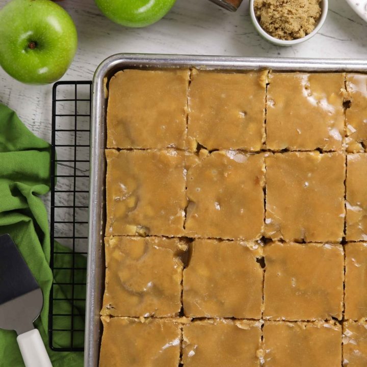 Glazed apple sheet cake in a pan cut into slices.