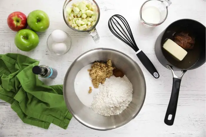 Apple sheet cake ingredients: flour, baking soda, salt, sugar, brown sugar, cinnamon, butter, apple butter, water, buttermilk, eggs, vanilla, and diced apple.