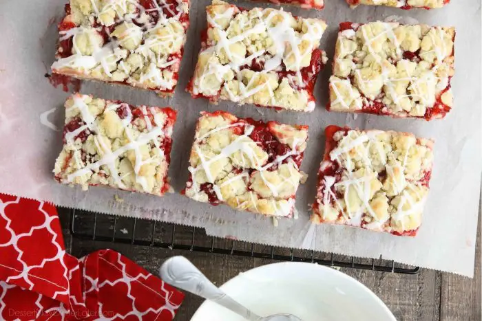 Cherry pie bars on top of parchment paper and a cooling rack.