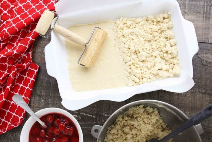 13x9-inch baking dish filled with shortbread crumbs, half of which have been rolled smooth with a rolling pin.