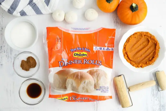 A bag of Rhodes Yeast Dinner Rolls surrounded by other ingredients in bowls, with a mini rolling pin on the side.