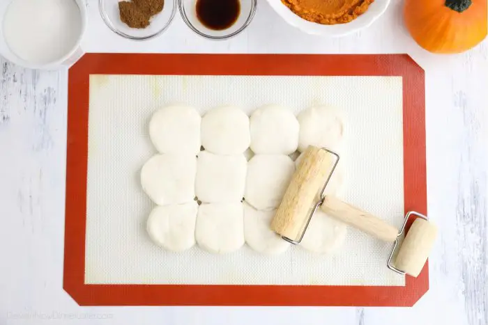 Twelve Rhodes dinner rolls being rolled flat with mini rolling pin.