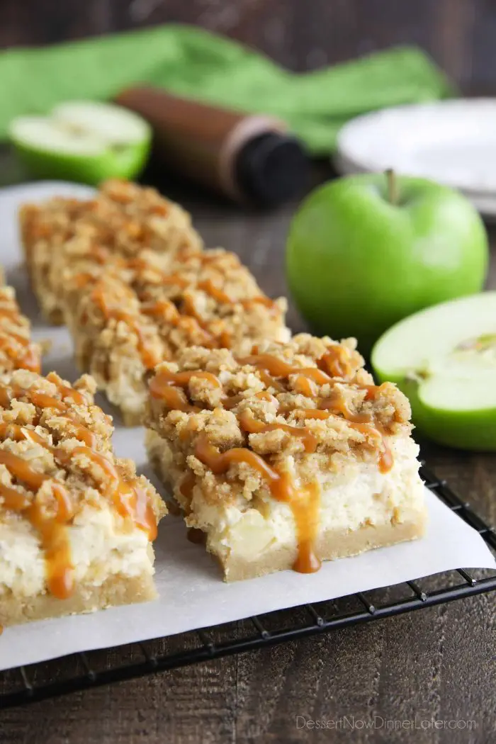 Caramel Apple Cheesecake Bars on a parchment lined wire cooling rack with caramel dripping down the sides.