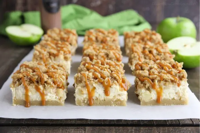 Caramel dripping down the sides of sliced apple cheesecake bars.