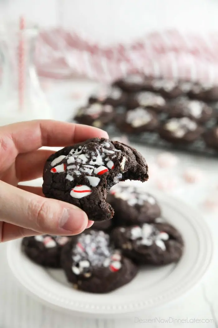 Bite taken out of a chocolate peppermint cookie with candy canes crushed on top.