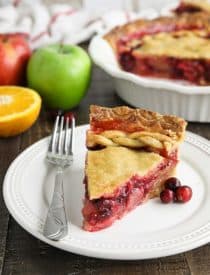 Slice of cranberry apple pie on plate with fork.