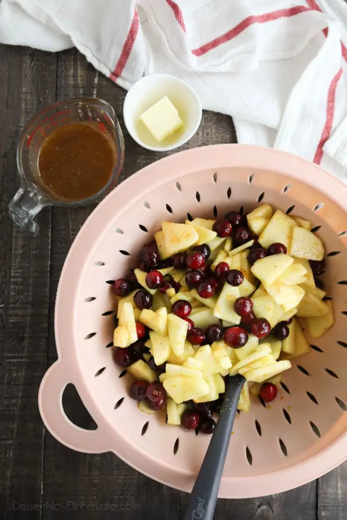 Cranberry apple pie filling being strained with a colander.