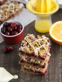 Cranberry Crumble Bars stacked with glaze drizzled on top.