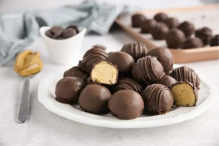 Easy peanut butter balls stacked on a plate focusing in on one that has been cut in half to show the inside.