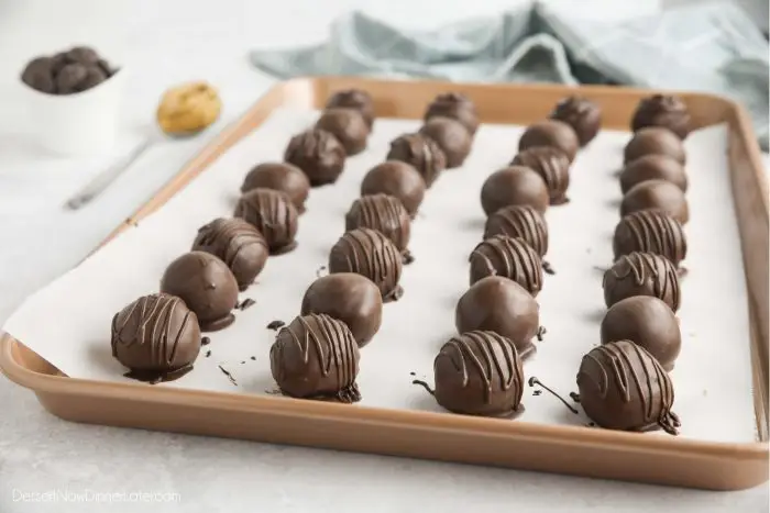 Dipped chocolate peanut butter balls on tray with parchment paper.
