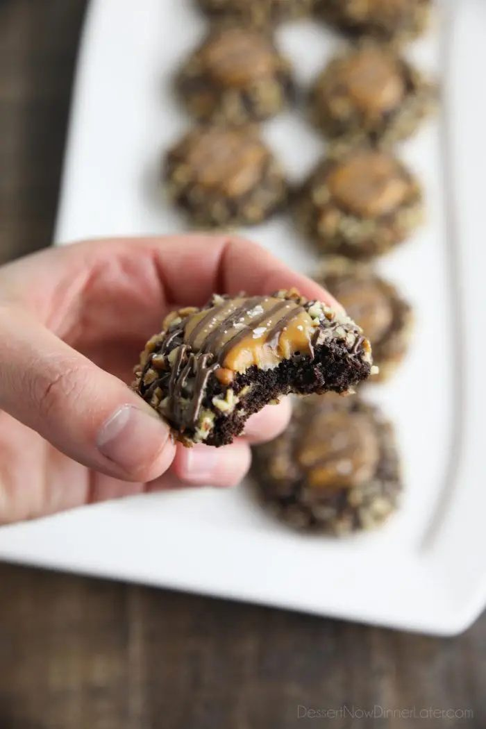 Bite taken out of a turtle thumbprint cookie to show texture on the inside of the chocolate cookie with a soft caramel center.