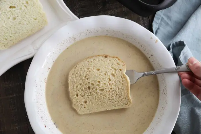 A slice of bread being soaked in French toast batter.