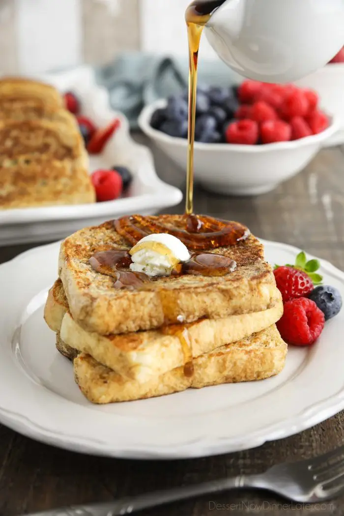 Classic French Toast stacked on a plate with syrup being poured over the top.